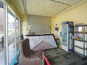 Un área de recepción con mostrador de mármol, zona de estar confortable, dispensador de agua y máquina expendedora.