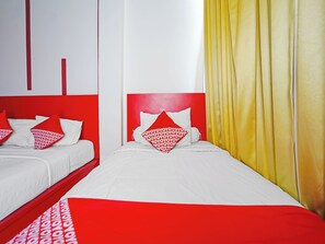 Habitación de hotel con dos camas, ropa de cama roja y blanca, y cortinas amarillas.