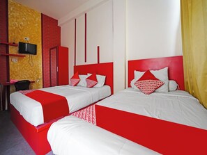 Una habitación de hotel con dos camas, televisión, escritorio y una silla.