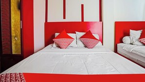 A hotel room with a large bed, red and white bedding, and a brick wall.