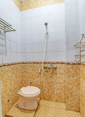 A small bathroom with a toilet, a shower, and a tiled floor. - Oyo 91480 Putridapisa Syariah (Bangil)