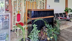 A reception area with a decorative entrance, a seating area, and potted plants. - Oyo 91480 Putridapisa Syariah (Bangil)