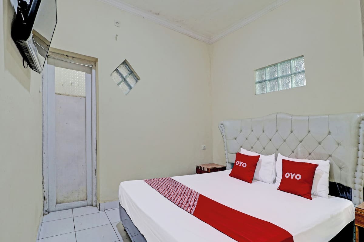 A hotel room with a bed, a small table, a window, and a door.