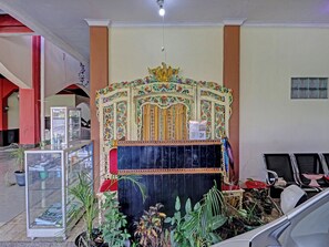 A room with a decorative altar, potted plants, and a glass display case. - Oyo 91480 Putridapisa Syariah (Bangil)