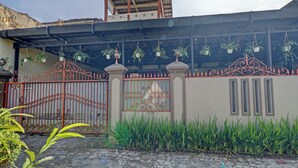 A gated entrance with a decorative iron gate, potted plants, and a building with a flat roof. - Oyo 91480 Putridapisa Syariah (Bangil)