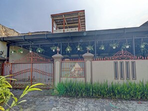 A gated entrance with a decorative iron gate, potted plants, and a building with a flat roof. - Oyo 91480 Putridapisa Syariah (Bangil)