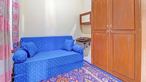 A room with a blue sofa, a wooden wardrobe, a small sink, and a patterned rug. - Oyo 91480 Putridapisa Syariah (Bangil)