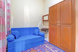 A room with a blue sofa, a wooden wardrobe, a small sink, and a patterned rug. - Oyo 91480 Putridapisa Syariah (Bangil)