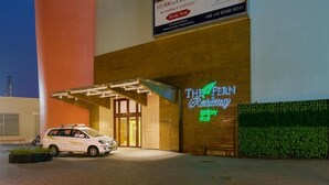 A hotel entrance with a covered driveway, a neon sign, and a parked car. - The Fern Residency Asansol (Asansol)