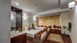 A hotel room with two beds, a desk, a chair, a TV, and a mirror. - The Fern Residency Asansol (Asansol)