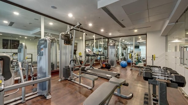 A gym with various exercise equipment, a bench, and dumbbells. - The Fern Residency Asansol (Asansol)