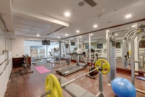 A gym with exercise equipment, a treadmill, and a mirrored wall. - The Fern Residency Asansol (Asansol)