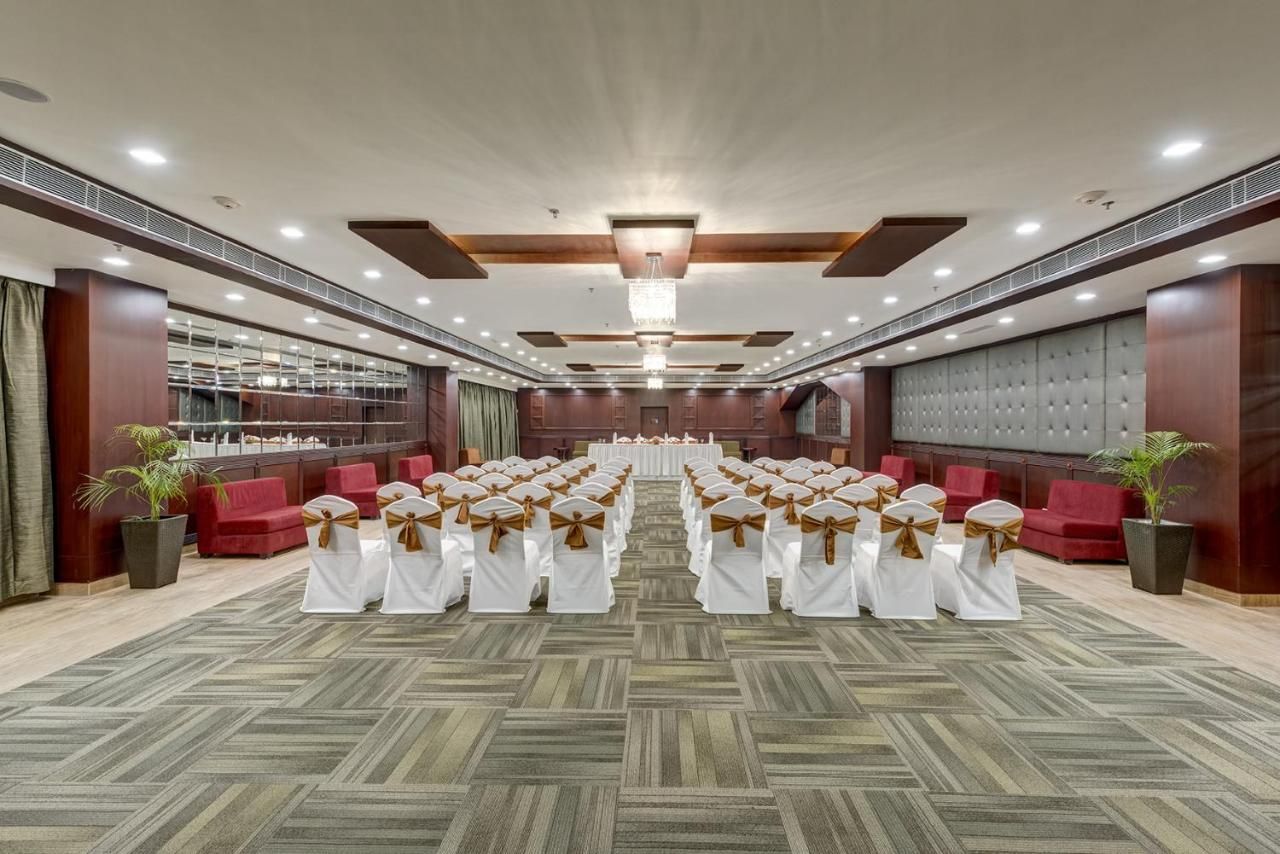 A conference room with rows of white chairs, a stage, and a large chandelier.