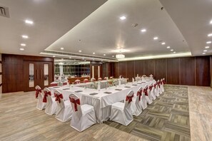 A conference room with a long table, white chairs with red sashes, and a chandelier. - The Fern Residency Asansol (Asansol)
