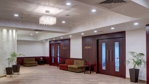 A spacious lobby with a chandelier, two sofas, and potted plants. - The Fern Residency Asansol (Asansol)