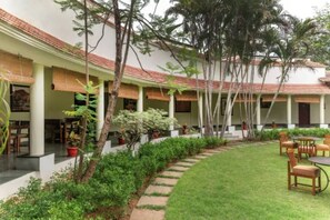 A courtyard with a central lawn, surrounded by covered seating areas and potted plants. - Sterling Arunai Anantha Tiruvannamalai (Tiruvannamalai)