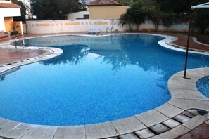 A swimming pool with a curved edge, a diving board, and a small bench. - Sterling Arunai Anantha Tiruvannamalai (Tiruvannamalai)