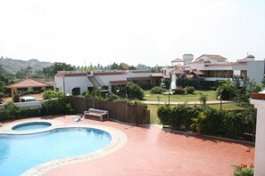 A residential area with a swimming pool, a covered patio, and a view of a hillside. - Sterling Arunai Anantha Tiruvannamalai (Tiruvannamalai)