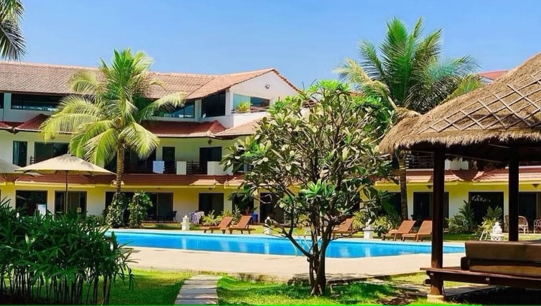 A hotel with a swimming pool, palm trees, and lounge chairs.