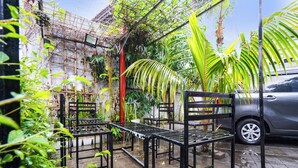 A garden with metal tables and chairs, a car, and a building with a metal fence. - Oyo 91561 Gandhi Hotel (Bandung)
