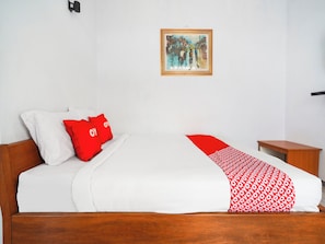 A bed with white and red bedding, a wooden headboard, and a painting on the wall. - Oyo 91561 Gandhi Hotel (Bandung)