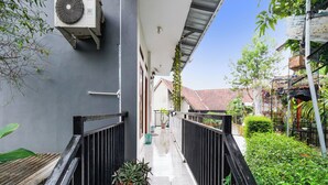A narrow corridor with a tiled floor, black railings, and potted plants. - Oyo 91561 Gandhi Hotel (Bandung)