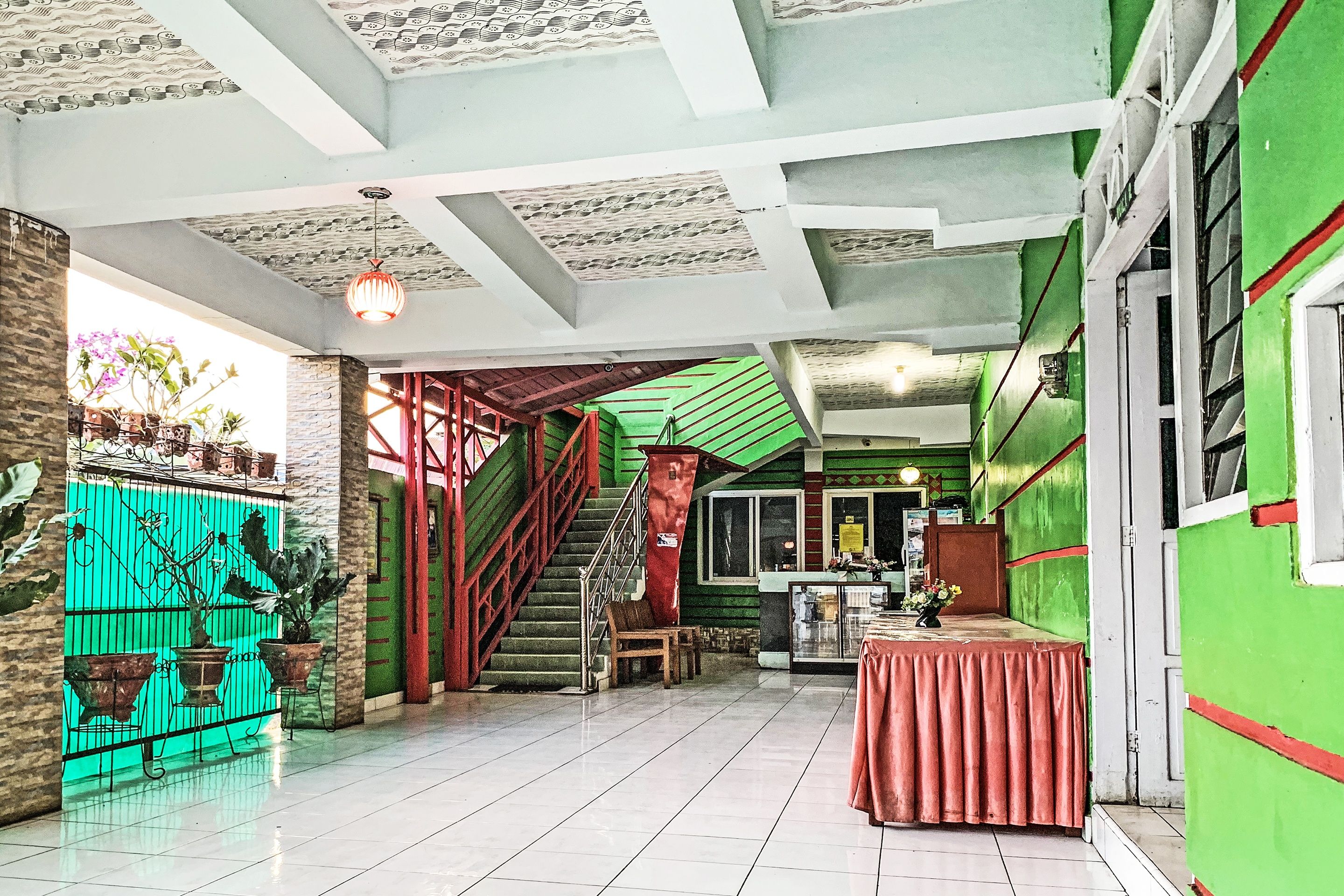 A spacious lobby with a staircase, potted plants, and a reception desk.