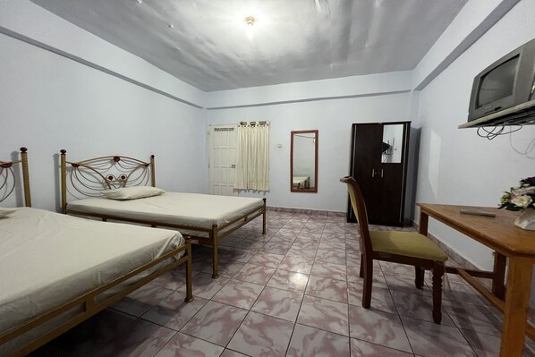 A room with two single beds, a wooden desk, a chair, a television, and a wardrobe. - Oyo 91757 Surya Hotel (Watansoppeng)