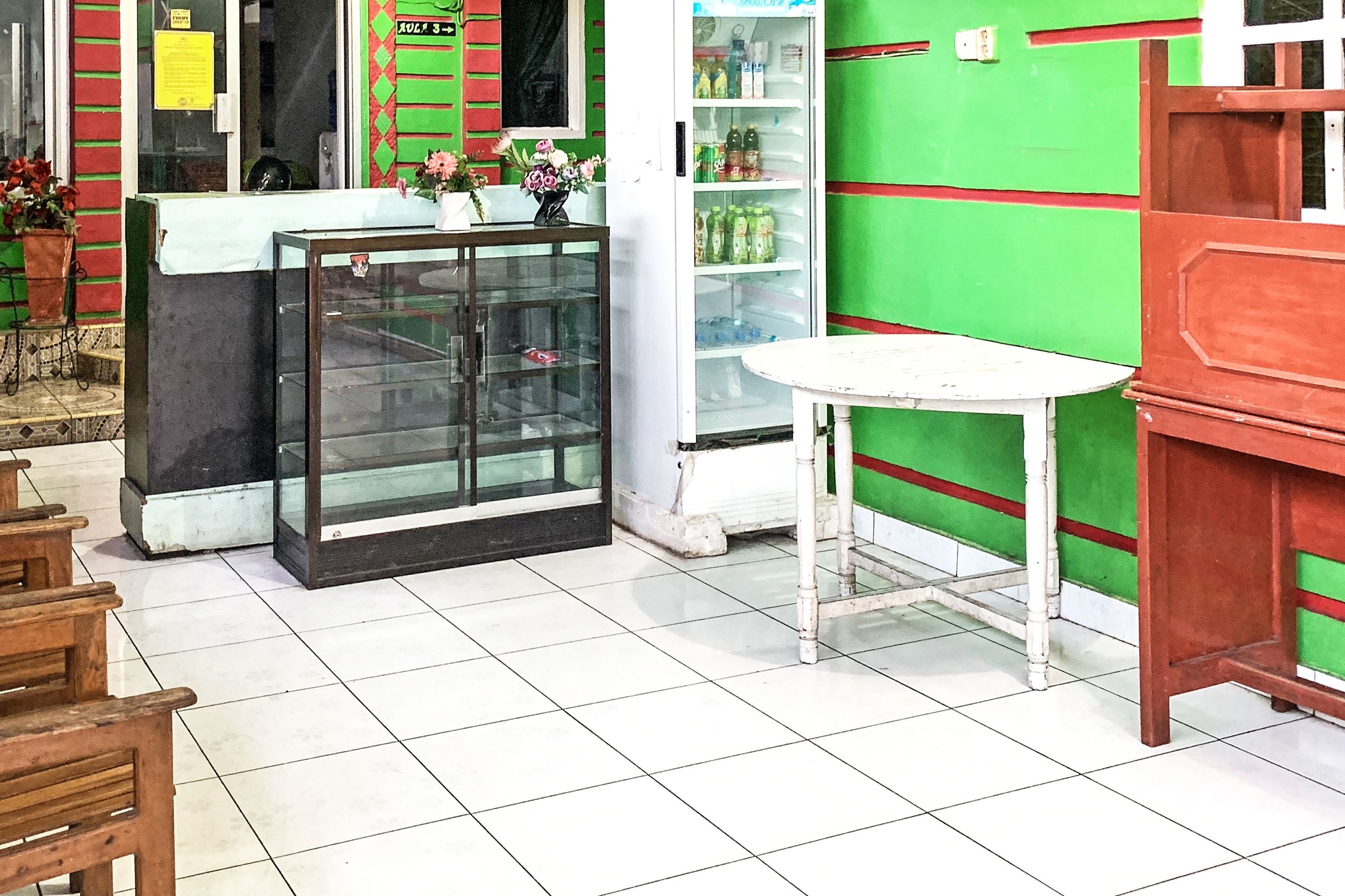A reception area with a glass display case, a white table, and a green wall with red stripes.