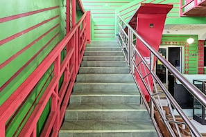 Una escalera con barandillas rojas y paredes verdes que conduce a un piso superior.