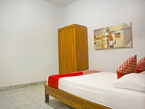 A bedroom with a wooden wardrobe, a bed with red and white bedding, and a painting on the wall. - Oyo 91456 Anggrek Homes Makassar (Makassar)