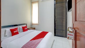 Habitación de hotel con cama, unidad de aire acondicionado, ventana con cortinas y puerta con letrero de 'No molestar'.