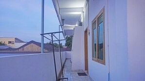 Un pasillo estrecho con un andamio metálico, una ventana con marco de madera y una puerta.