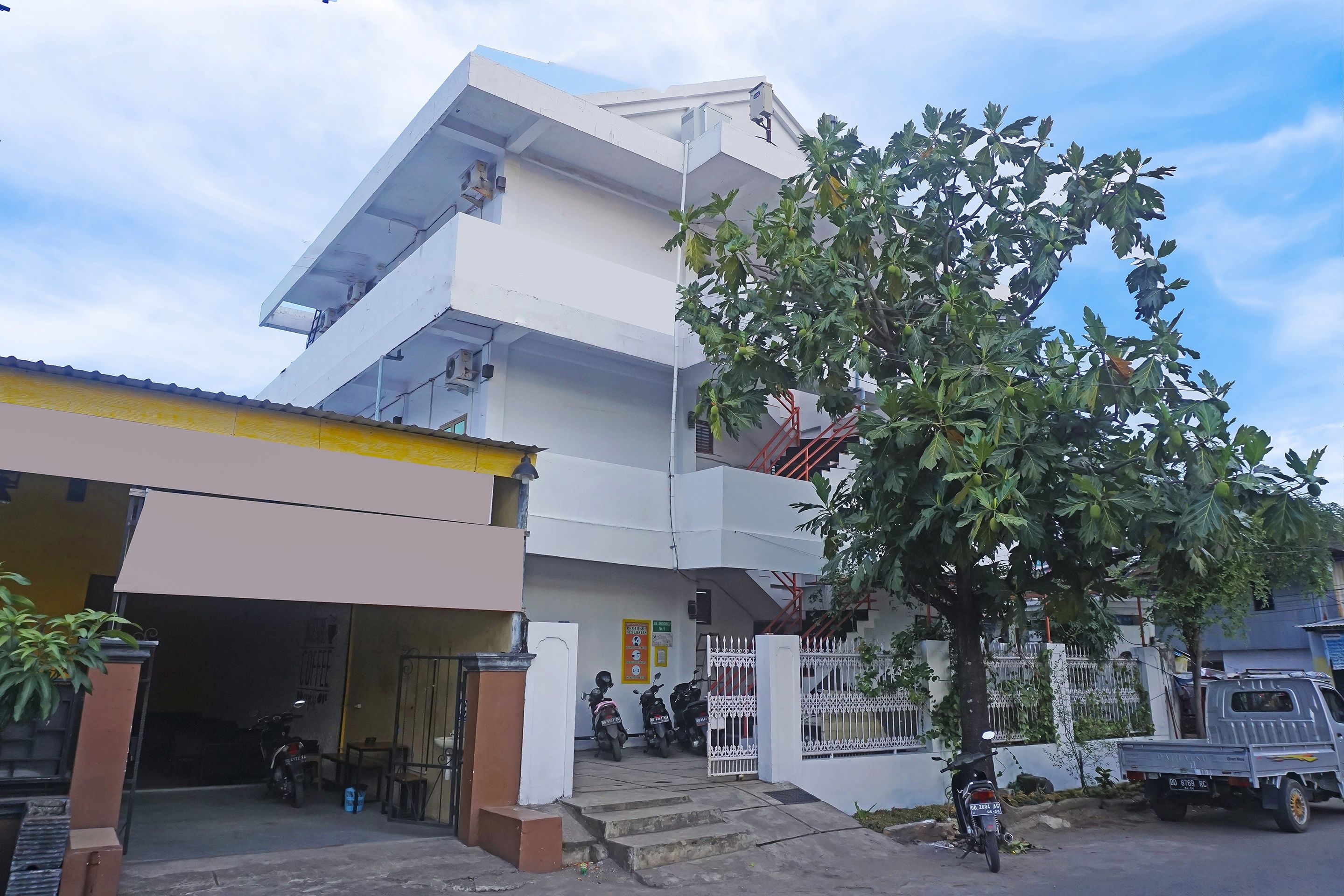 A multi-story residential building with a garage, a tree in front, and a parked truck.