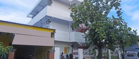 A multi-story residential building with a garage, a tree in front, and a parked truck.