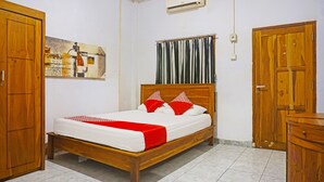 Un dormitorio con cama de madera, colcha roja y blanca y armario de madera.