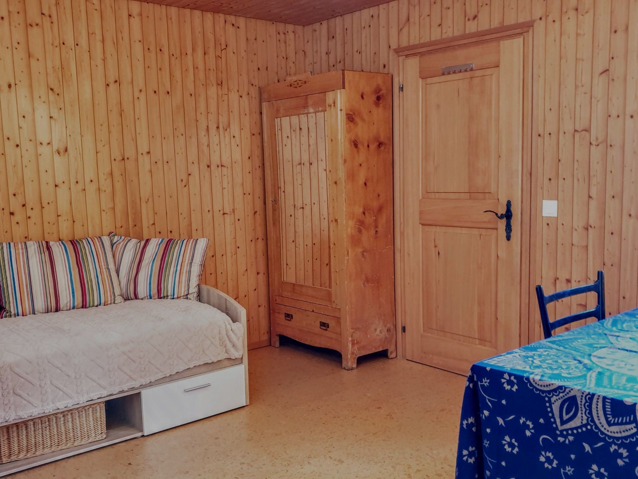 Ein Zimmer mit einem Bett, einem Kleiderschrank, einem Tisch mit Tischdecke und einem Stuhl.