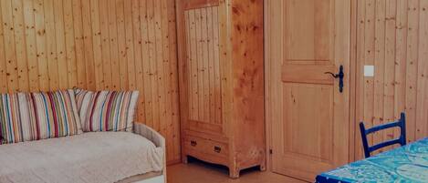 Ein Zimmer mit einem Bett, einem Kleiderschrank, einem Tisch mit Tischdecke und einem Stuhl.