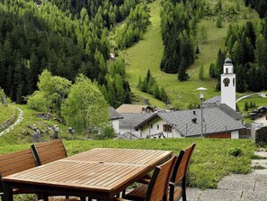 A wooden table and chairs in a rural setting with a church and a clock tower in the background. - Starlera, (Innerferrera), by Interhome (Innerferrera)