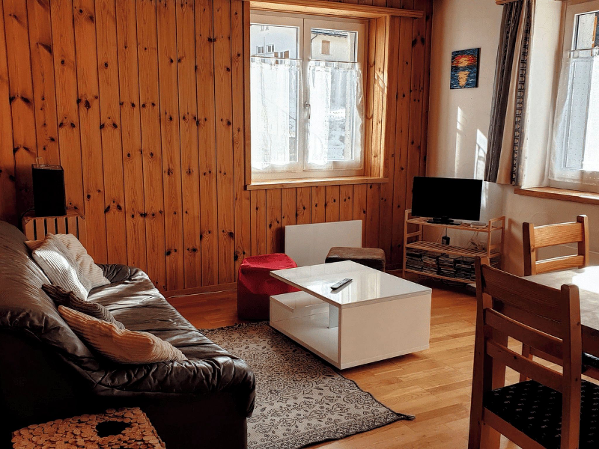 Tunnelmallinen olohuone, jossa on nahkasohva, valkoinen sohvapöytä ja televisio puisen jalustan päällä.