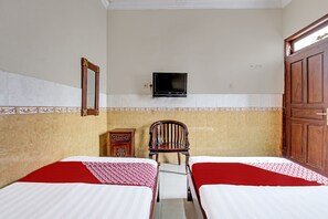 Ett hotellrum med två sängar, en tv, en trästol och en garderob.