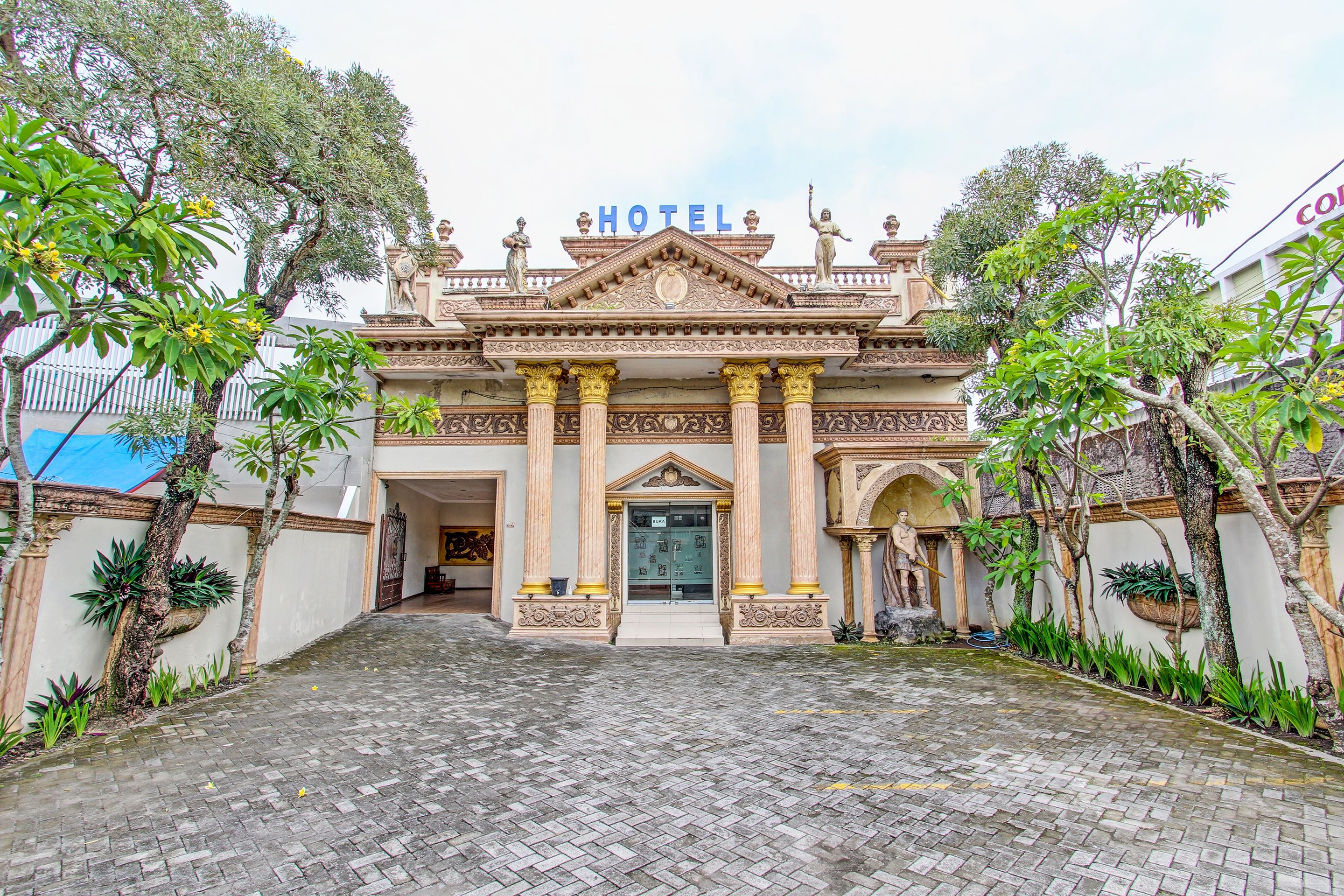 A hotel entrance with a grand facade, columns, and statues.