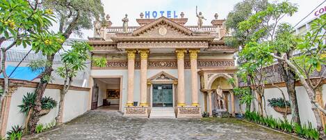 A hotel entrance with a grand facade, columns, and statues.