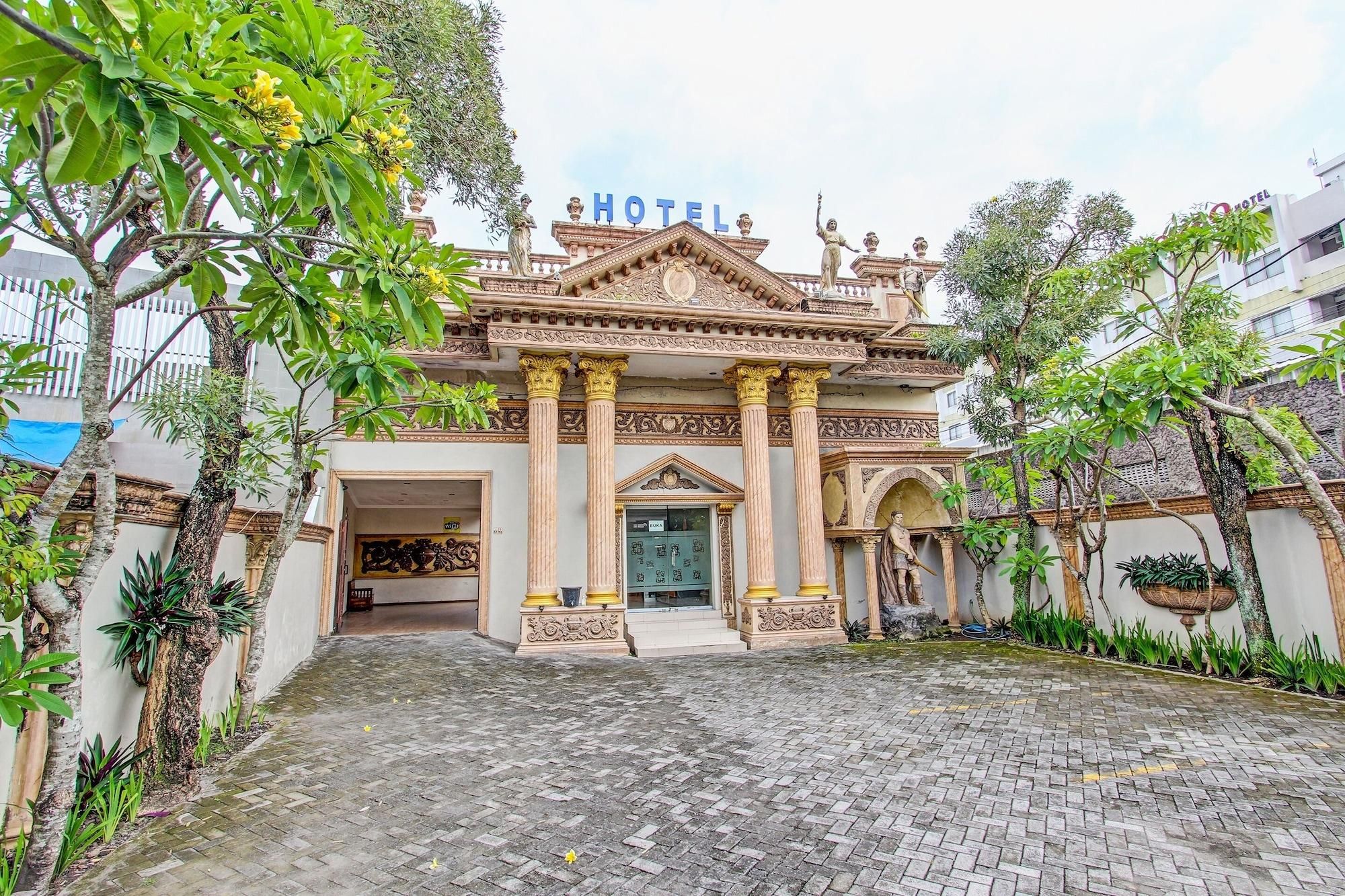 A hotel with a traditional architectural style, featuring a central entrance with columns, a balcony, and a statue.