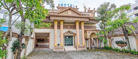 A hotel with a traditional architectural style, featuring a central entrance with columns, a balcony, and a statue.