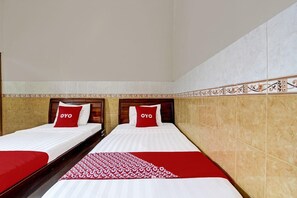 A hotel room with two beds, each with a red and white bedspread and pillows, and a patterned red runner. - Hotel Srikandi Kalasan (Kalasan)
