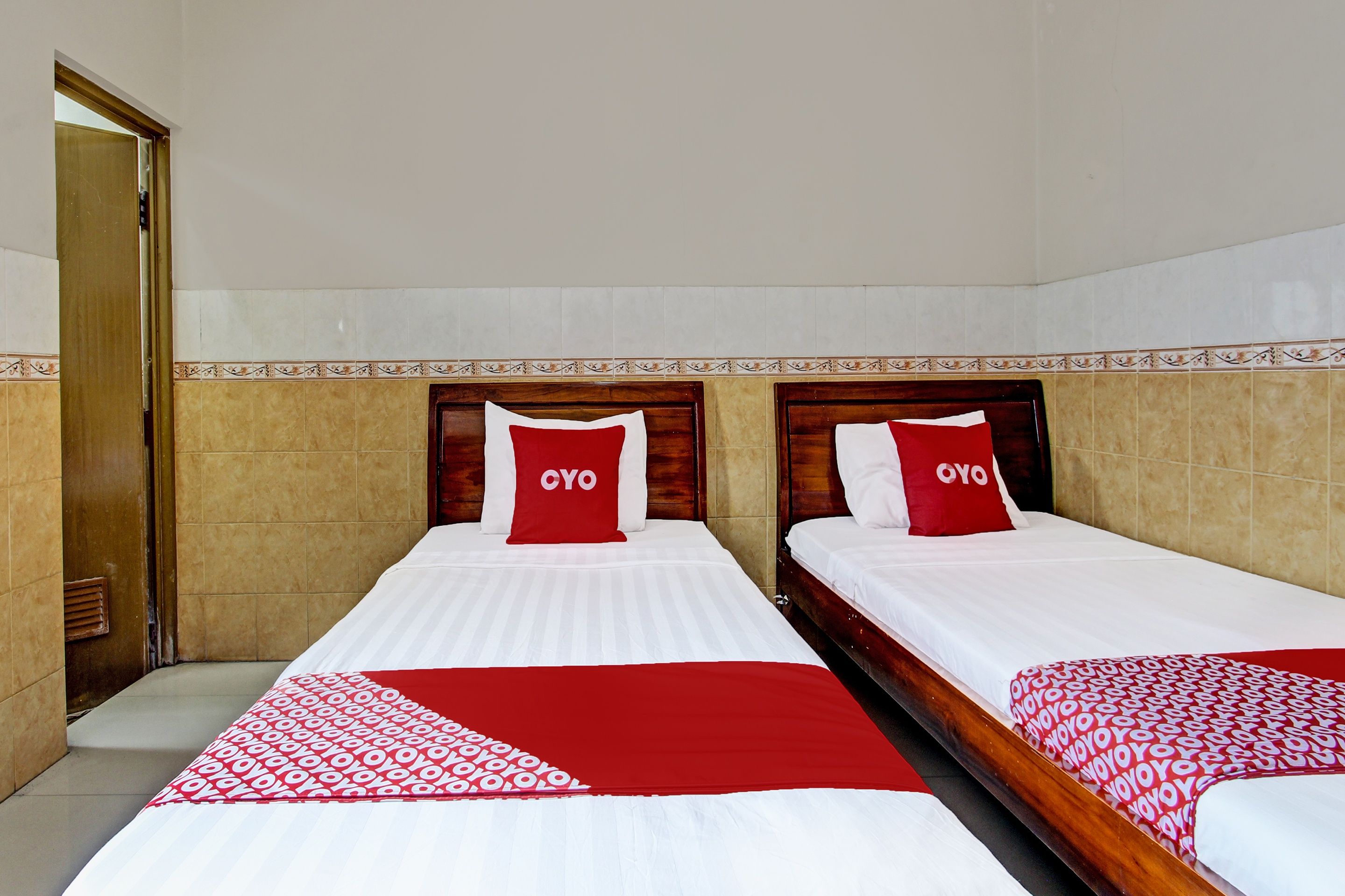Habitación de hotel con dos camas, cada una con cubrecama rojo y blanco y almohadas a juego.