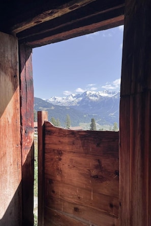 A wooden cabin with a view of snow-capped mountains.