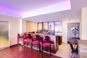 A bar area with a counter, multiple chairs, and a variety of bottles. - The Fern Denzong Hotel And Spa, Gantok (Gangtok)