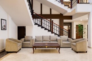 Una sala de estar moderna con un conjunto de sofás, una mesa de centro y una escalera.
